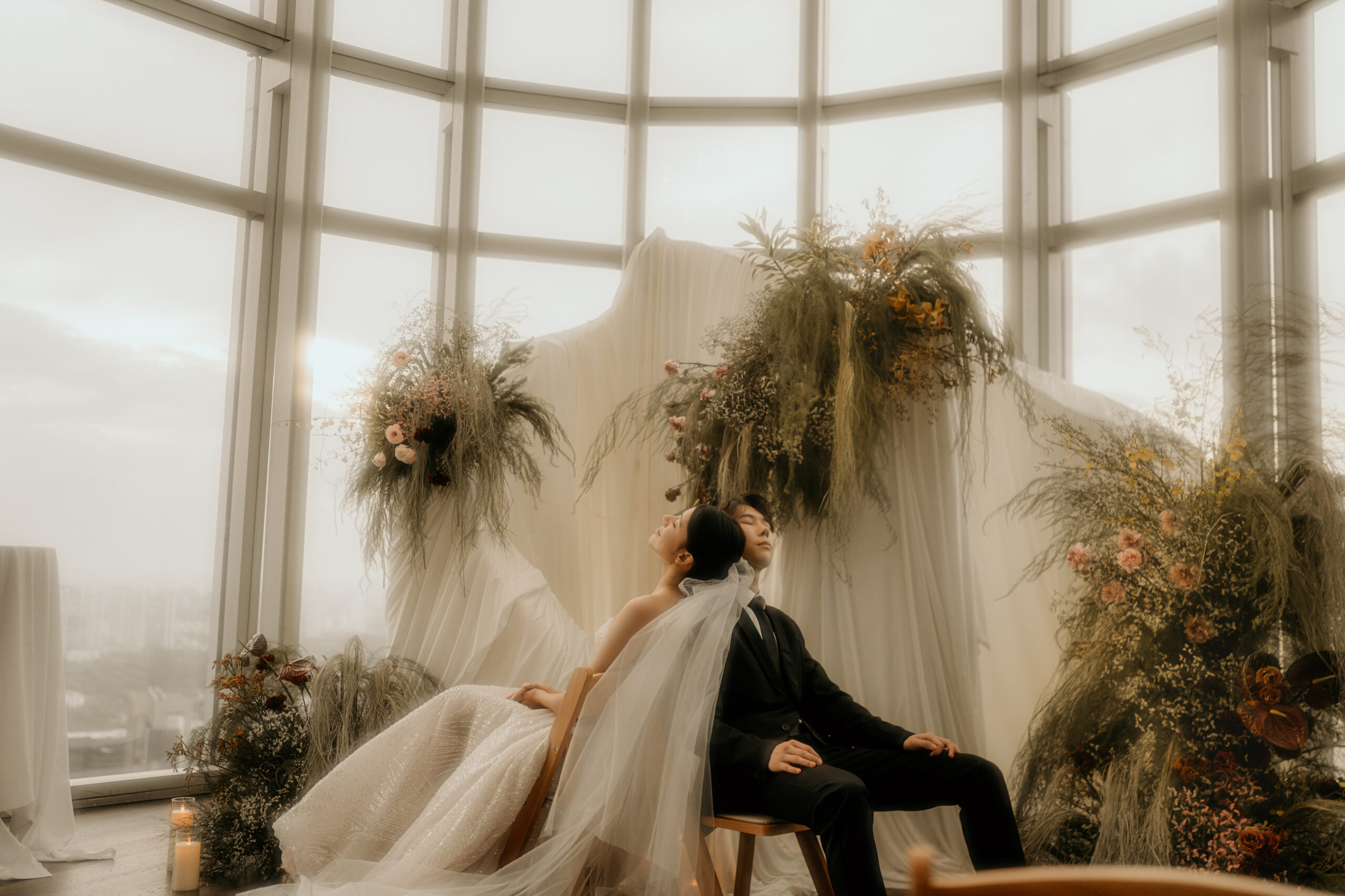 Couple beneath a dried floral installation by the curved skyline windows at 1-Atico
