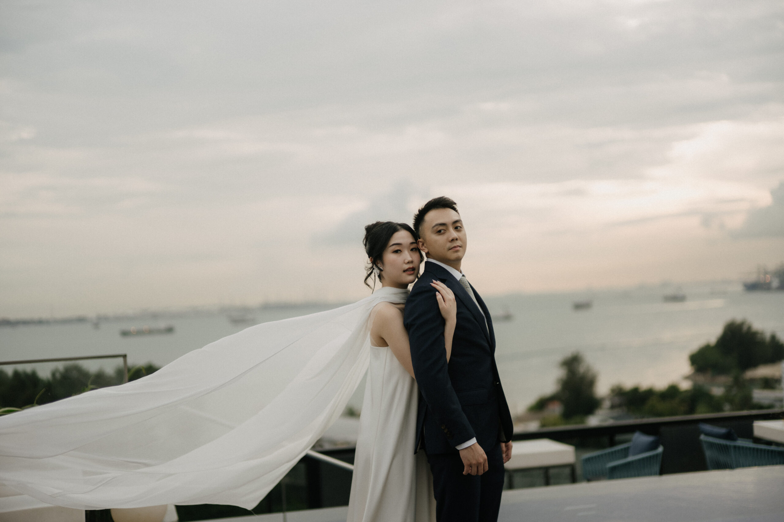 Bride and groom on a coastal rooftop overlooking the sea at dusk
