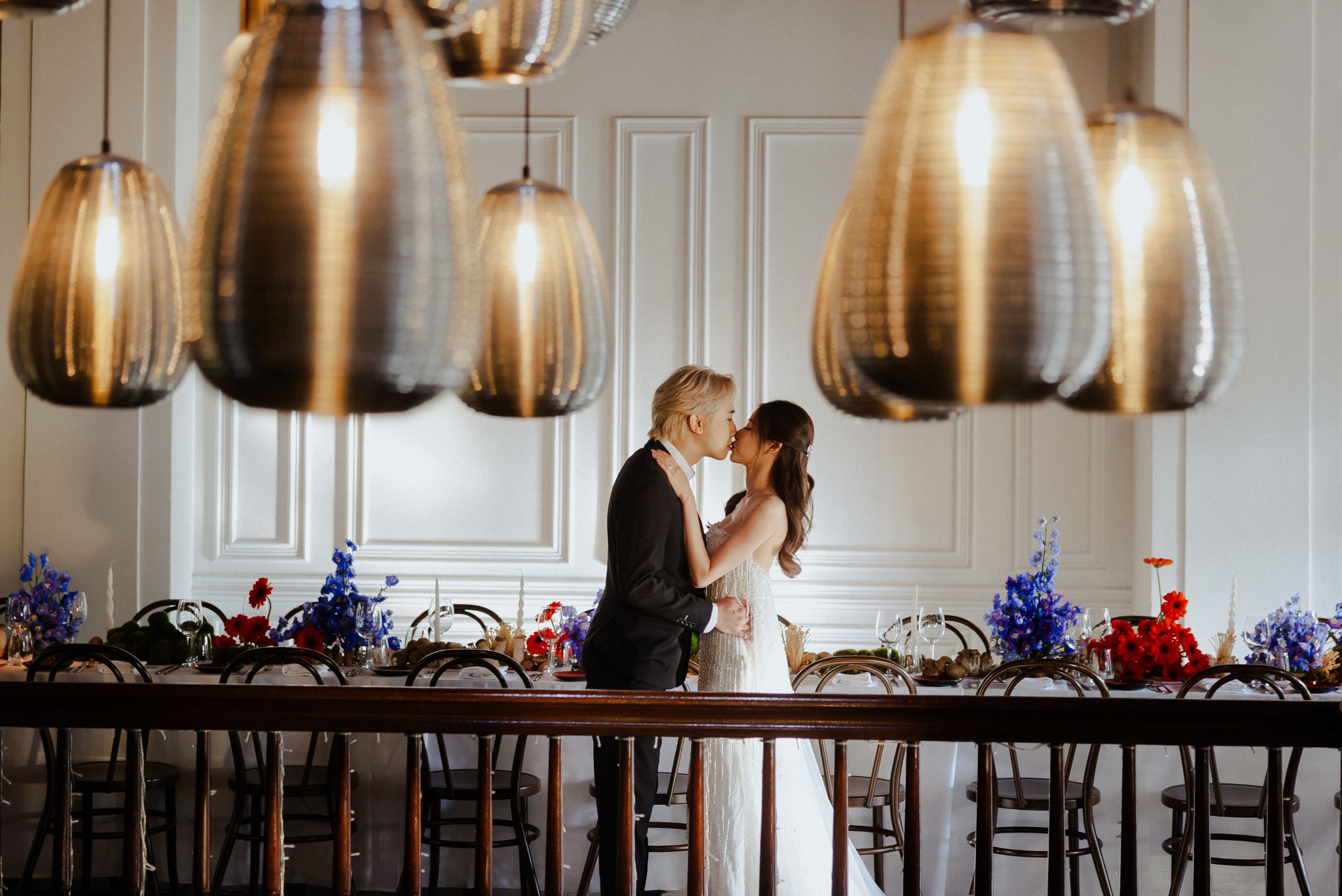 Couple embracing at a long dinner table beneath sculptural pendant lamps