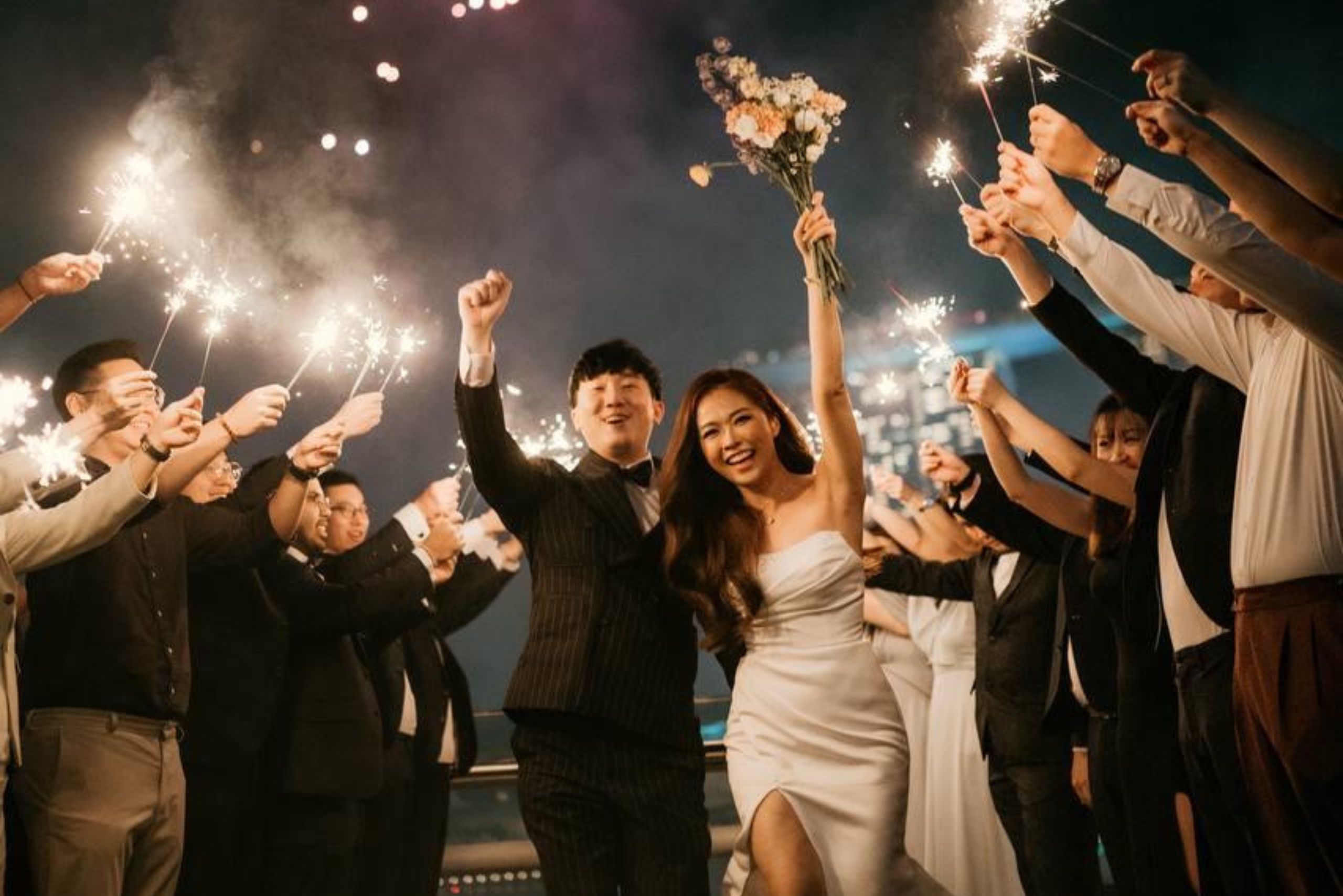 Guests raising sparklers as the newlyweds make their night-time rooftop send-off